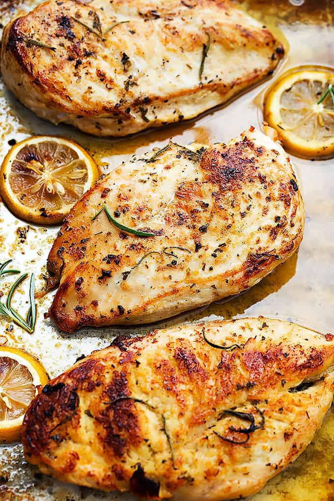 baked lemon chicken on a sheet pan with lemon wedges and fresh rosemary - one of the recipes for this week's healthy weekly meal plan