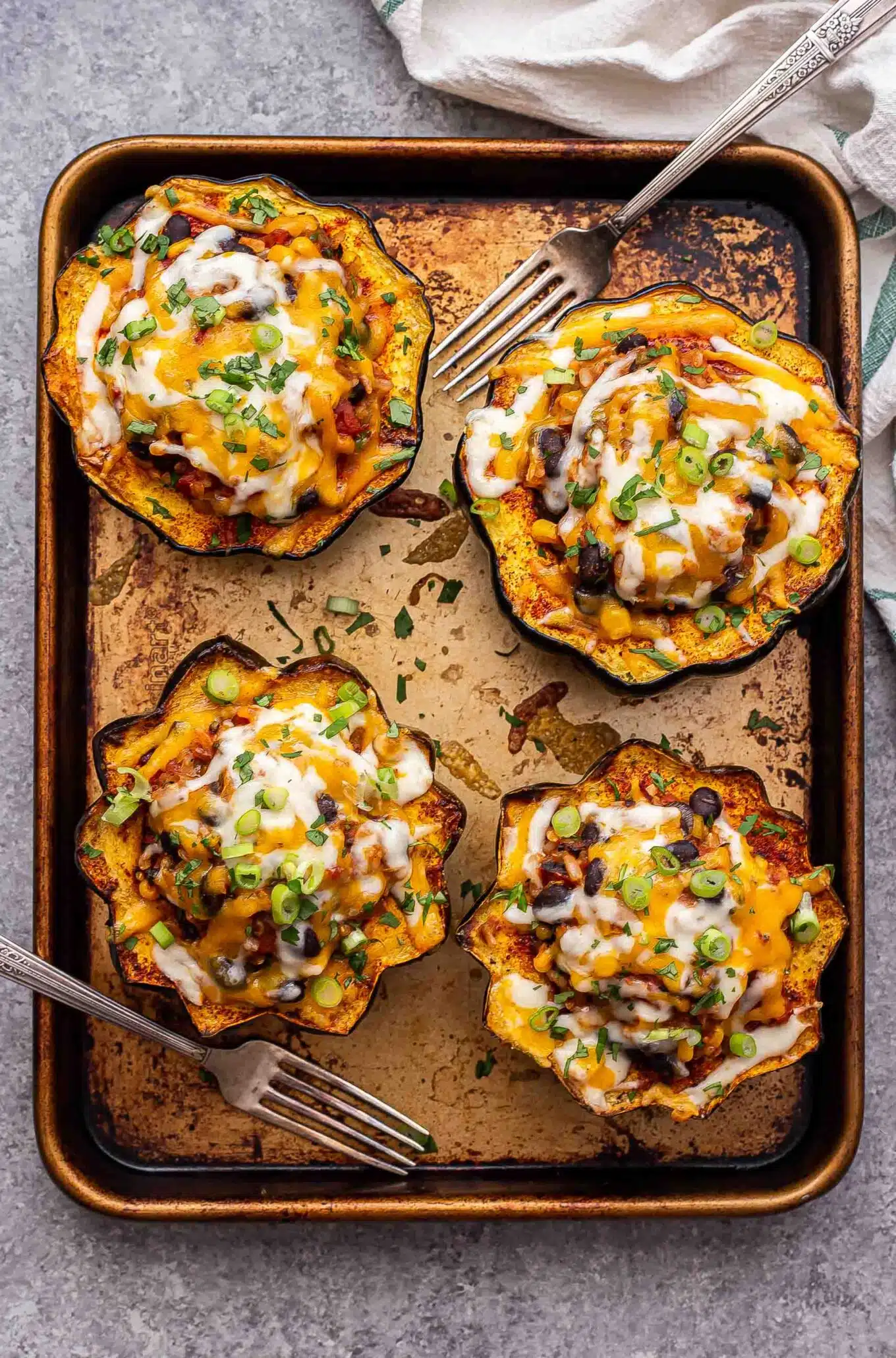 4 Southwest Stuffed Acorn Squash on a rimmed sheet pan with two forks - one of the recipes for this week's healthy weekly meal plan